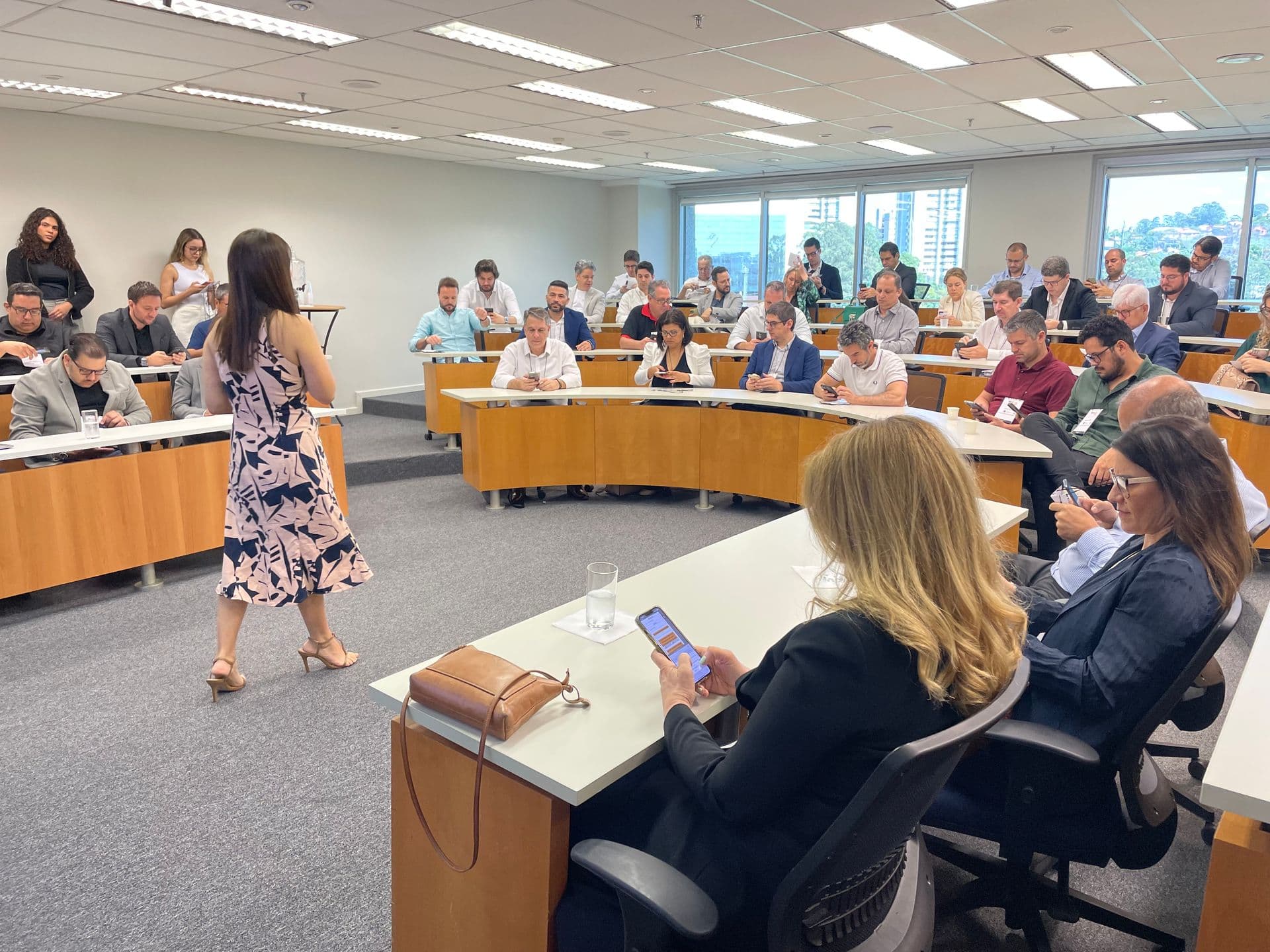 Turma de executivos em sala de aula com a professora conduzindo a discussão